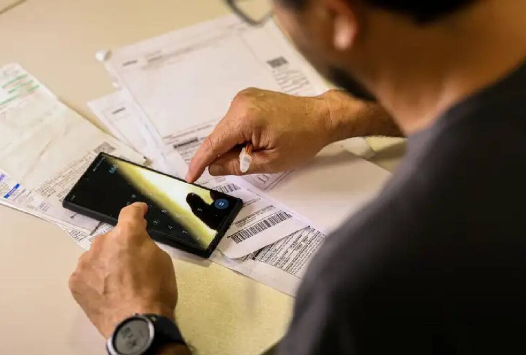 Homem segurando caneta e usando calculadora