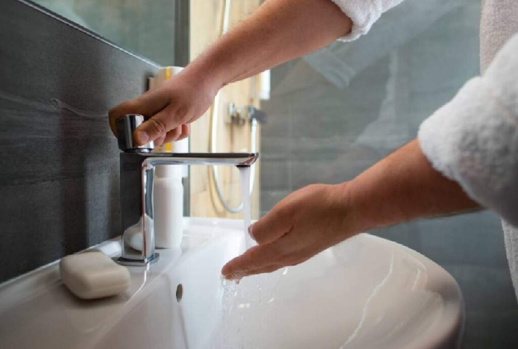 Pessoa lavando as mãos no banheiro