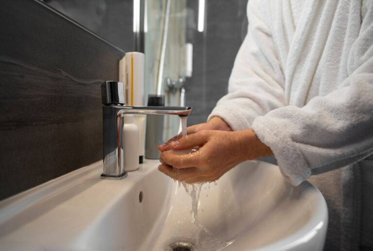 Mulher lavando às mãos na pia do banheiro