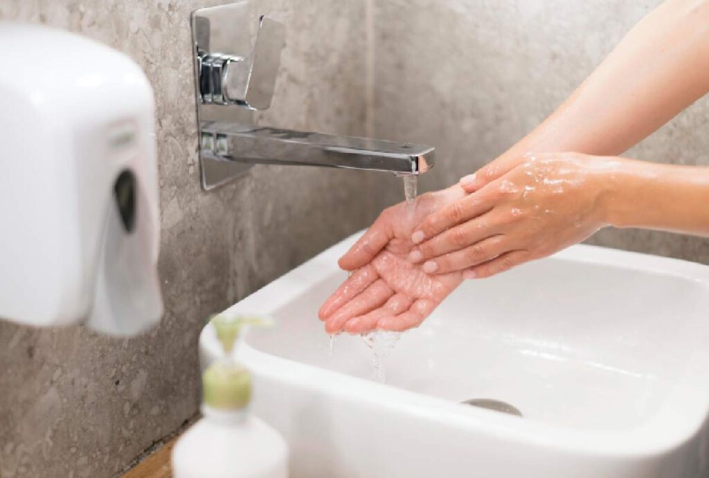 Pessoa lavando as mãos no banheiro