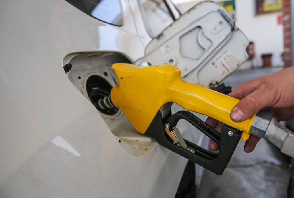 Carro branco sendo abastecido em posto de gasolina