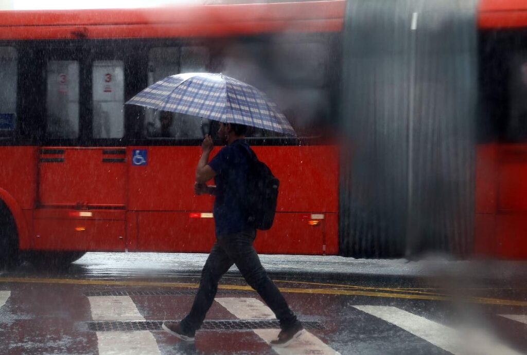 Homem andando na chuva segurando um guarda-chuva