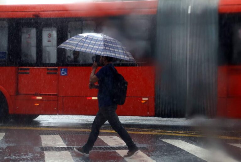 Homem andando na chuva segurando um guarda-chuva