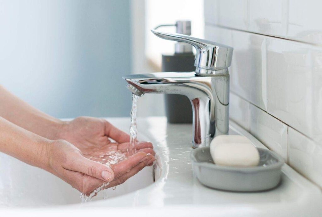 Pessoa lavando a mão na pia