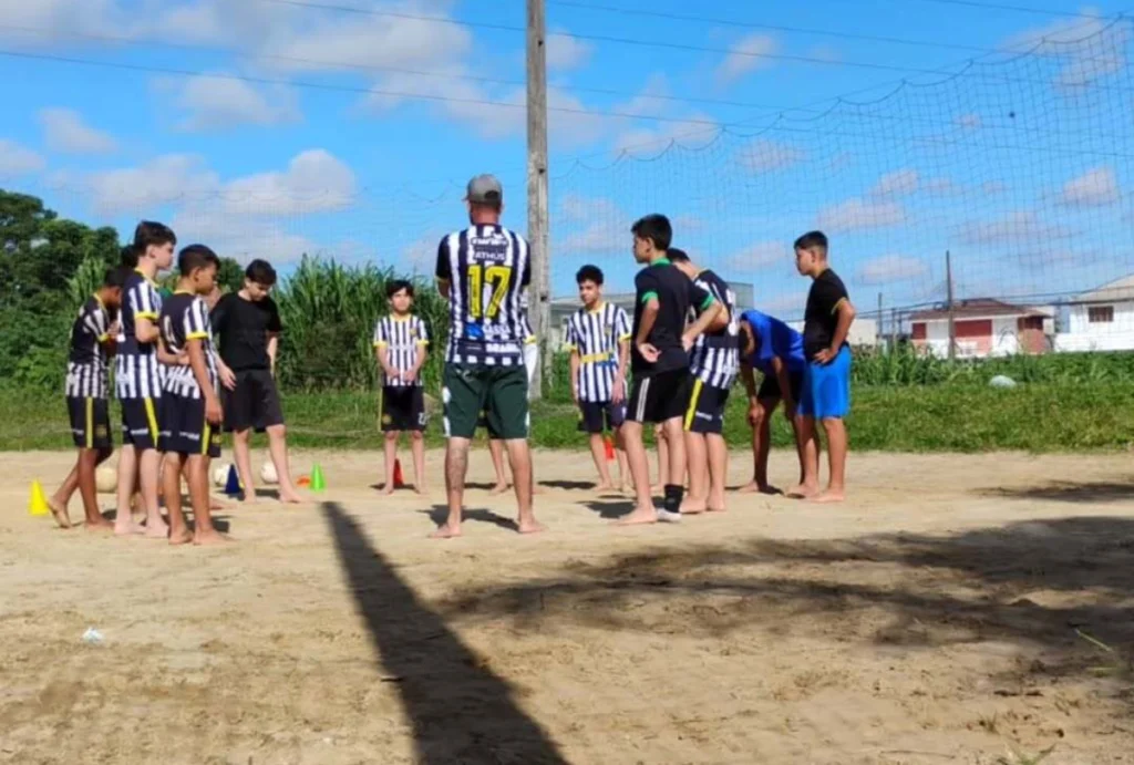 Projeto social D’Quebrada, reunido em um campinho de areia onde ocorre os treinos.